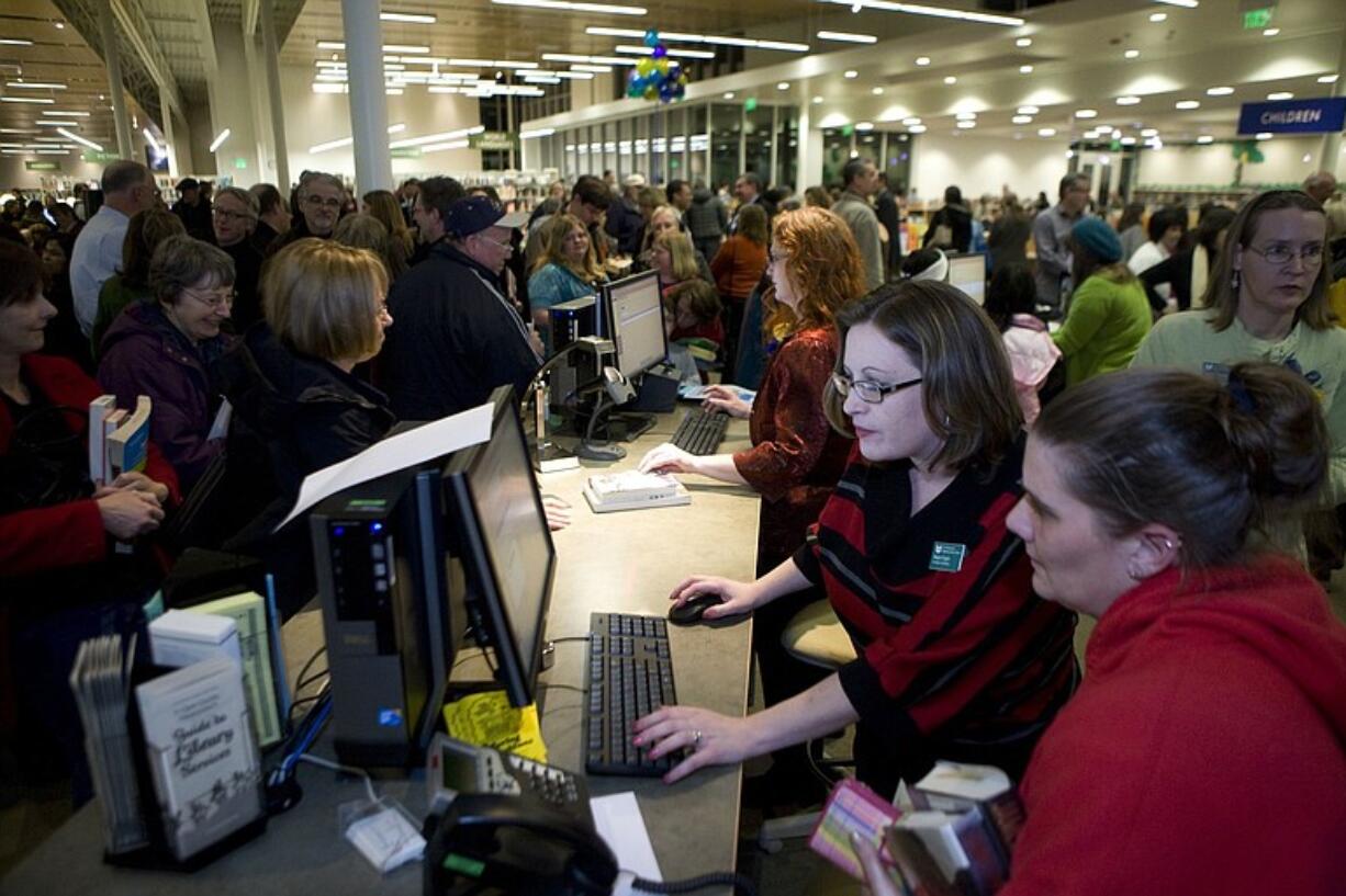 Megan Dugan, second from right, a circulation clerk, helps Heather Cyr, right, hceck out books after the Cascade Park Community Library grand opening on Tuesday.