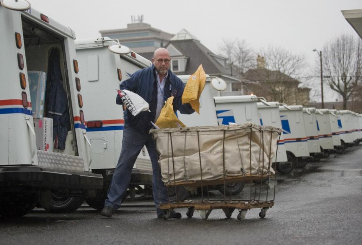 Zachary Kaufman/The Columbian
Scott McHale, a 31-year veteran mail carrier, swings packages into his mail truck in west Vancouver Monday. &quot;This is the most chaotic I've ever seen it,&quot; McHale said.