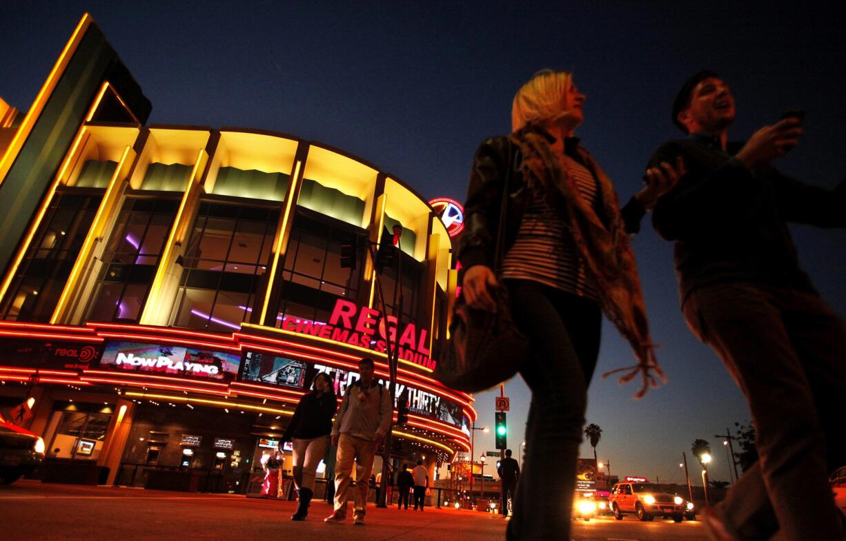 People walk in front of the Regal Cinemas LA Live Stadium 14 in Los Angeles in 2013. After a recent spate of violence in movie theaters this summer, Regal Entertainment Group adopted a new companywide policy instructing its employees to check any backpacks, packages or other bags customers are carrying before letting them in to see a movie.