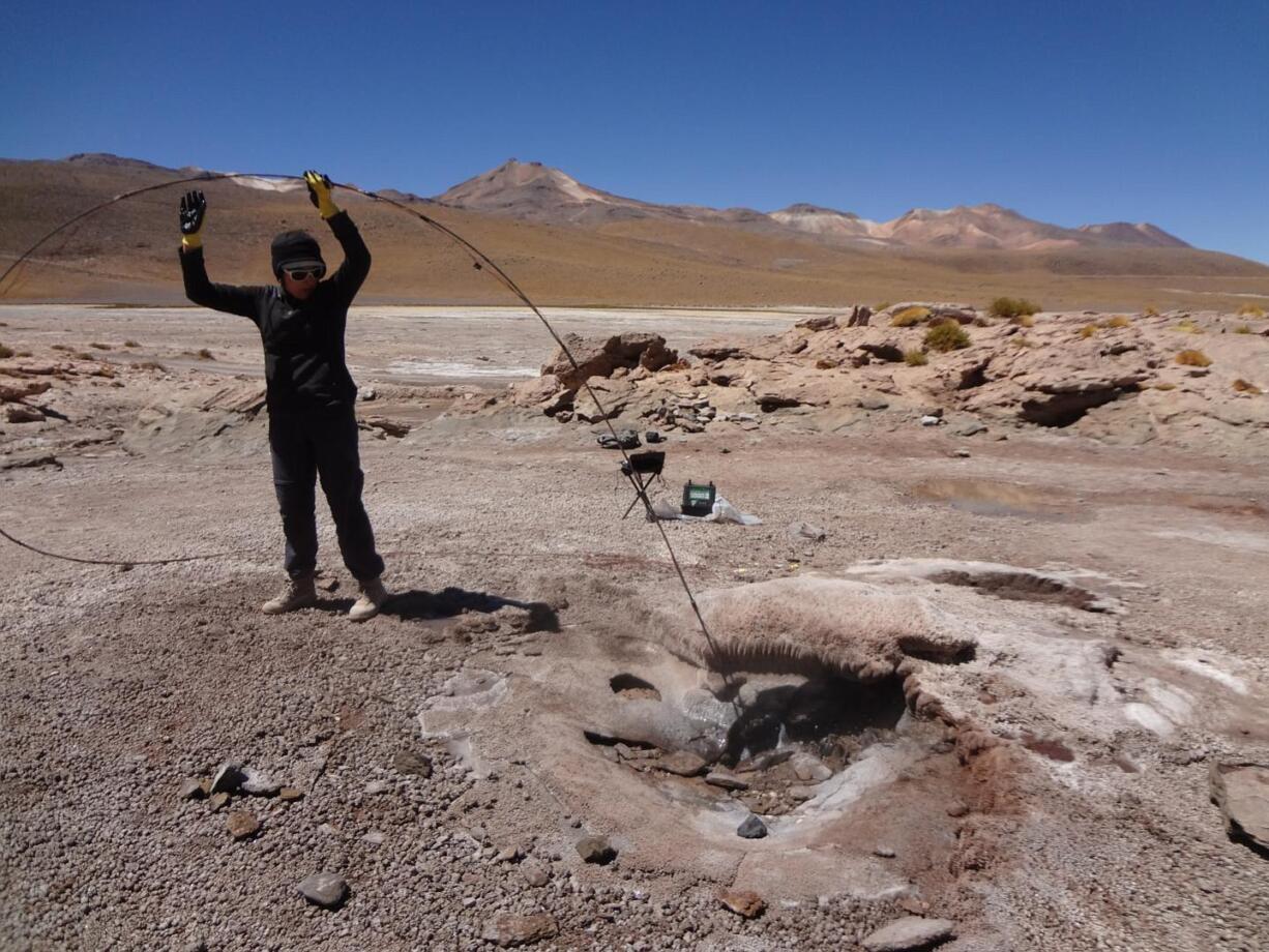 A researcher threads temperature and pressure sensors down a geyser hole in Chile's Atacama desert.