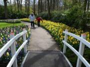 A French couple heads toward a bridge, flanked by tulips at Keukenhof in Holland.