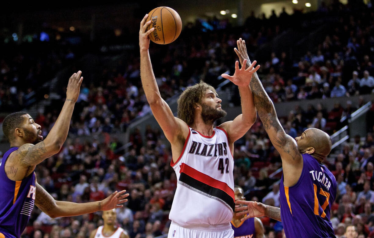 Portland Trail Blazers center Robin Lopez, center, shoots over Phoenix Suns forward P.J. Tucker, right, and forward Markieff Morris, left, during the third quarter of an NBA basketball game in Portland, Ore., Monday, March 30, 2015.