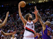 Portland Trail Blazers center Robin Lopez, center, shoots over Phoenix Suns forward P.J. Tucker, right, and forward Markieff Morris, left, during the third quarter of an NBA basketball game in Portland, Ore., Monday, March 30, 2015.