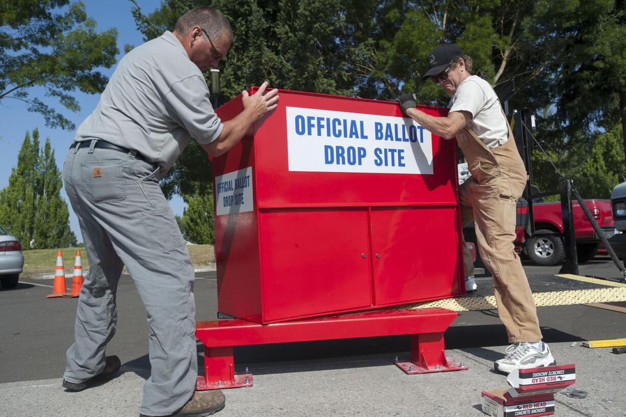 County employees Kevin Haggerty, left, and Gary Pratka instal la ballot drop-off box at the Fisher's Landing Transit Center in Vancouver on Wednesday.