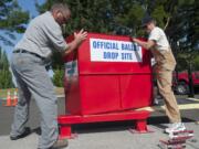 County employees Kevin Haggerty, left, and Gary Pratka instal la ballot drop-off box at the Fisher's Landing Transit Center in Vancouver on Wednesday.