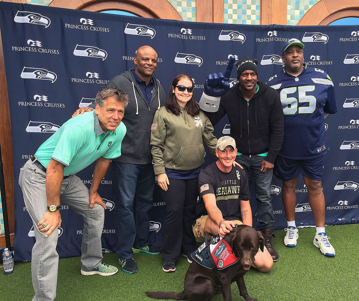 John Kaiser, his wife, Tina, and his Northwest Battle Buddies service dog, Ruger, pose for a picture with former Seattle Seahawks Jim Zorn, Warren Moon, Jordan Babineaux and Edwin Bailey.