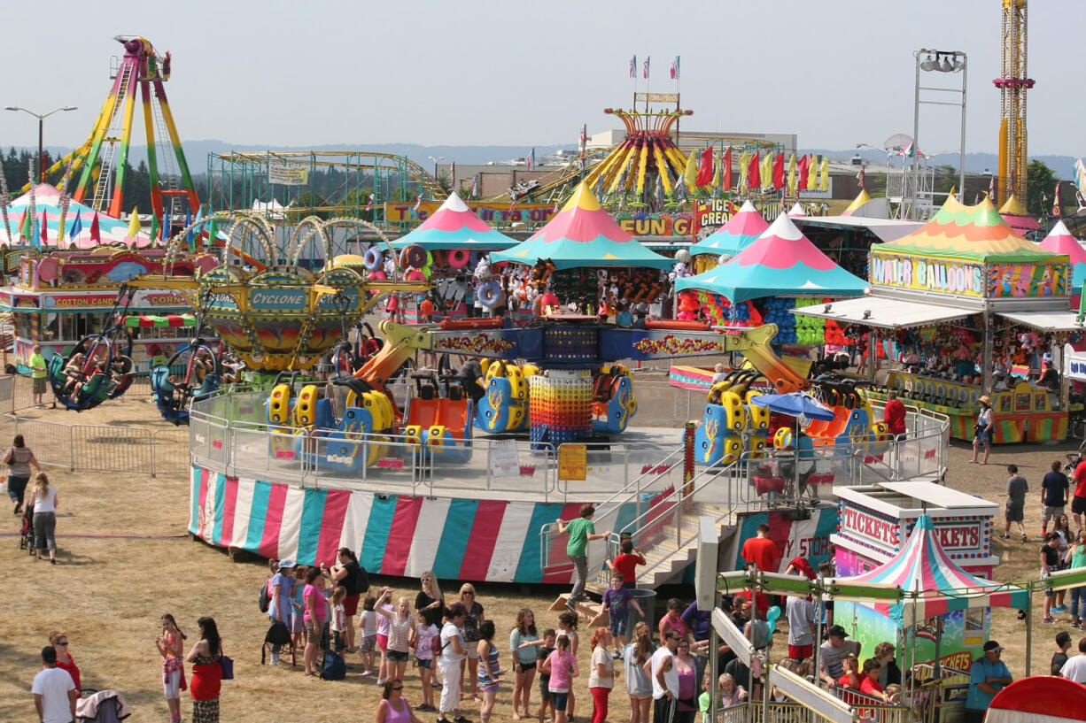 A big view of the Clark County Fair carnival in 2014. Top, from left: Never fear, animal lovers: goats, chickens, cows, pigs, horses and llamas are all still on hand. Clark County Fair marketing director Matt Ferris, right, explores the Superhero Adventure cityscape while Kyle Paradis, co-owner of Vendetta Productions, pauses during construction. Paul Fletcher of Seattle builds the paintball booth at the Clark County Fairgrounds earlier this week. Angie Cervantes rides the merry-go-round at the 2014 Clark County Fair.