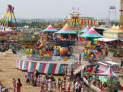 A big view of the Clark County Fair carnival in 2014. Top, from left: Never fear, animal lovers: goats, chickens, cows, pigs, horses and llamas are all still on hand. Clark County Fair marketing director Matt Ferris, right, explores the Superhero Adventure cityscape while Kyle Paradis, co-owner of Vendetta Productions, pauses during construction. Paul Fletcher of Seattle builds the paintball booth at the Clark County Fairgrounds earlier this week. Angie Cervantes rides the merry-go-round at the 2014 Clark County Fair.