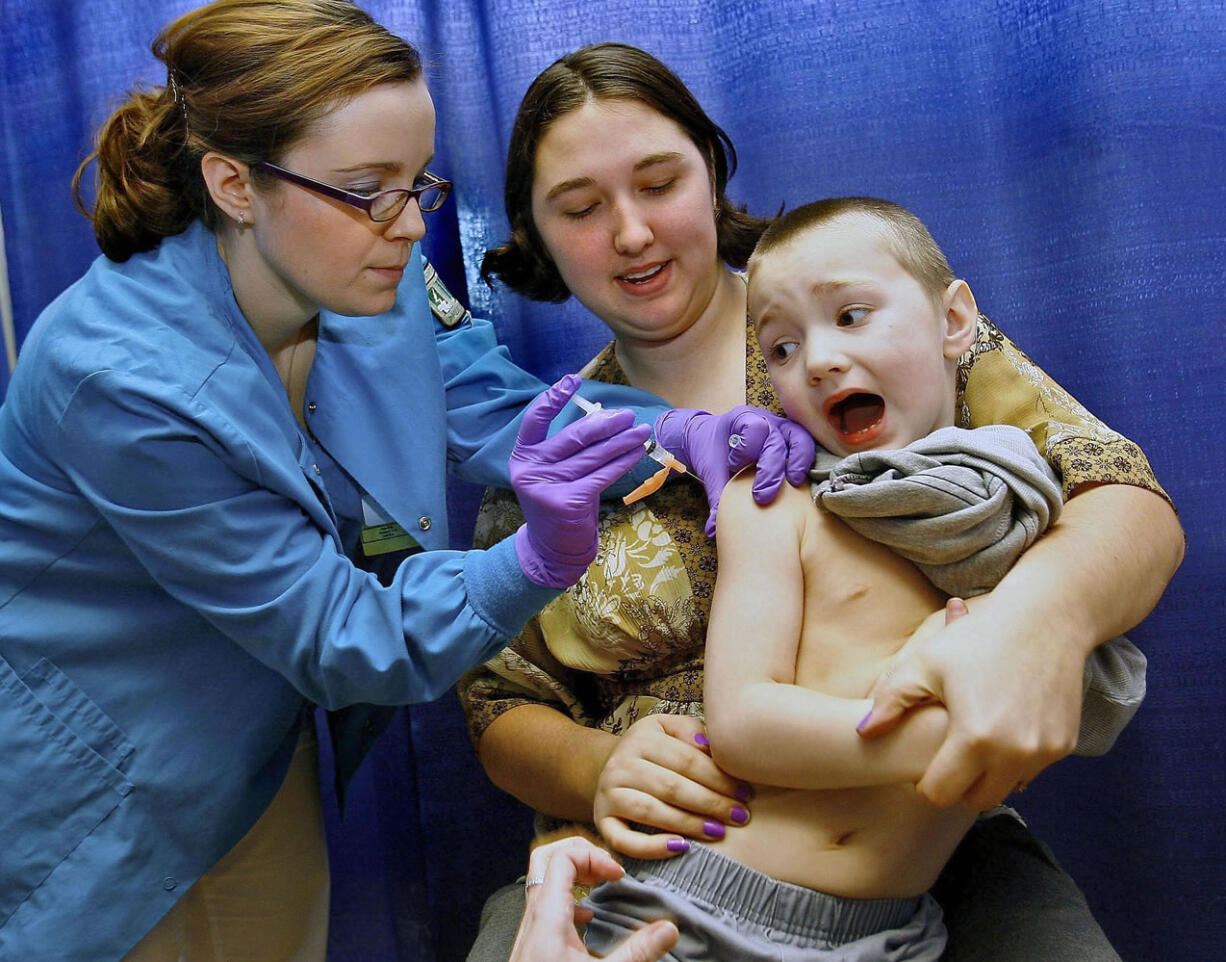 Anton Sheperd, 4, attempts a quick escape while his mother Tiffany Adkins holds him and nursing student Tiffany Stacy administers a shot at a February 2009 immunization clinic in Roseburg, Ore.