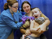 Anton Sheperd, 4, attempts a quick escape while his mother Tiffany Adkins holds him and nursing student Tiffany Stacy administers a shot at a February 2009 immunization clinic in Roseburg, Ore.