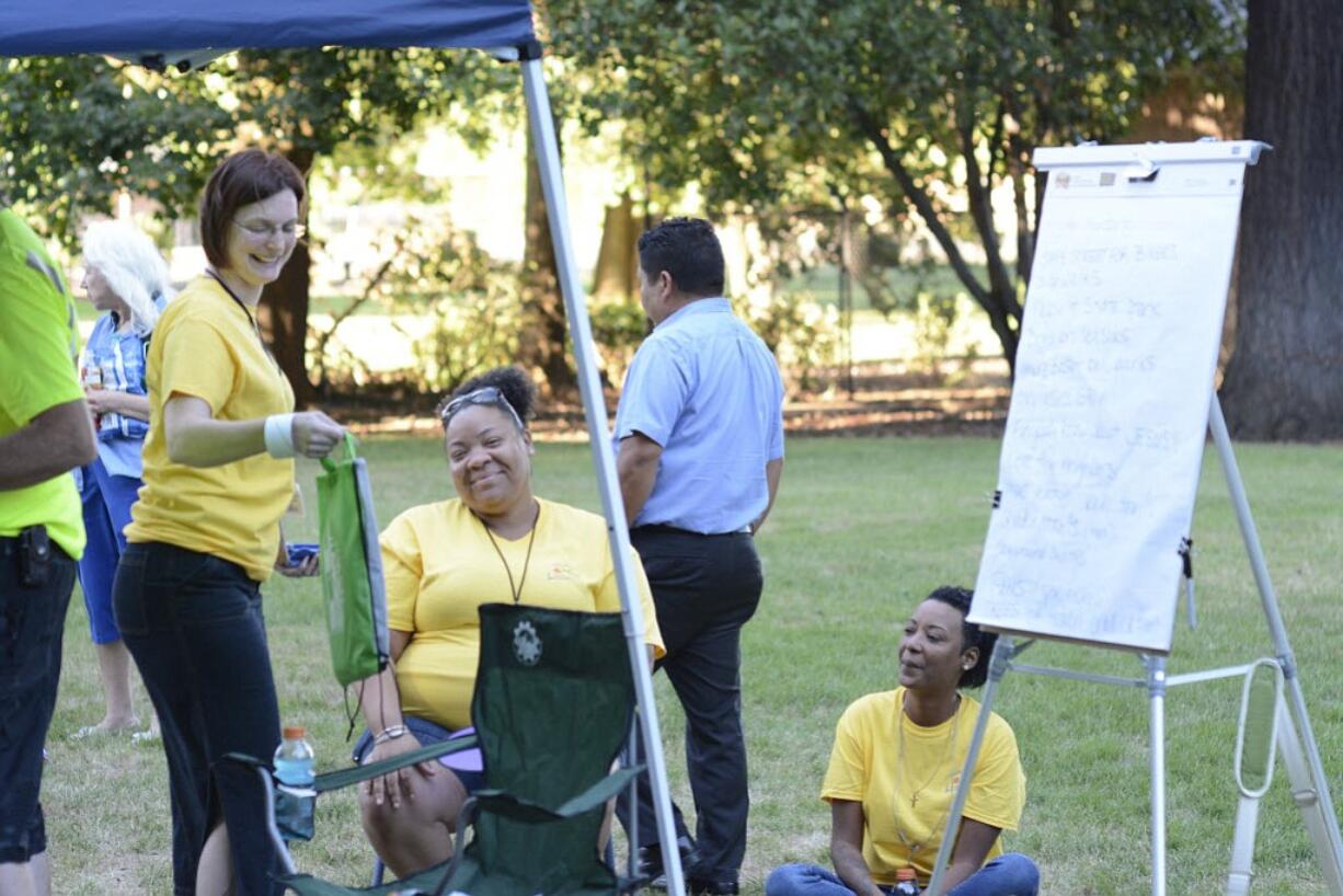 Justin Runquist/The Columbian
Heather England, left, Brandi Williams, center, and Connie Wellman, right, celebrate National Night Out on Tuesday at Water Works Park in Vancouver. The women worked with several neighborhood associations to organize the event, which encourages community members and police to work together in crime prevention.