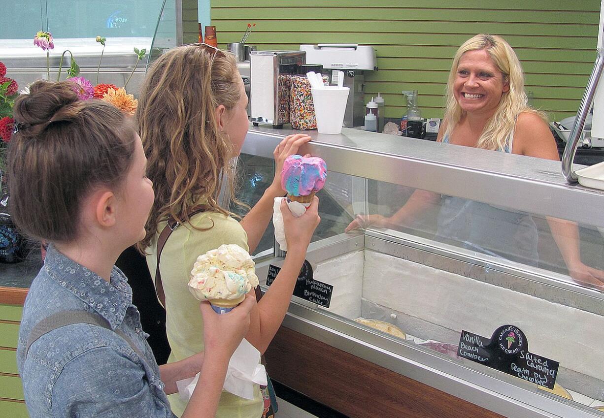 Charity Groza (right) served up scoops of Cascade Glacier ice cream for customers Thursday, at the recently reopened Lakeside Country Store, in Camas. Groza, Mikki Keller and Tom Savageau are leasing the building.