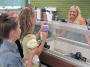 Charity Groza (right) served up scoops of Cascade Glacier ice cream for customers Thursday, at the recently reopened Lakeside Country Store, in Camas. Groza, Mikki Keller and Tom Savageau are leasing the building.