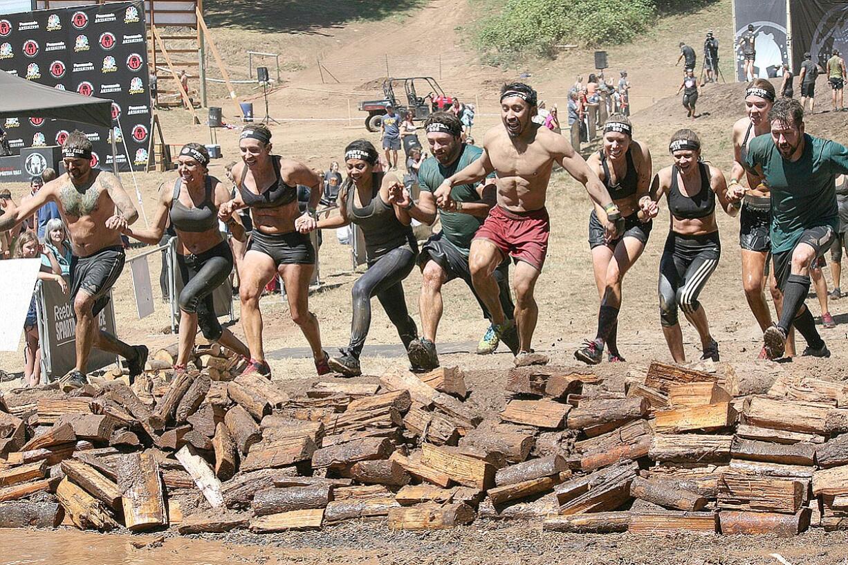 A team of Spartans takes the plunge into muddy water and then crosses the finish line together Saturday, at Washougal Motocross Park.