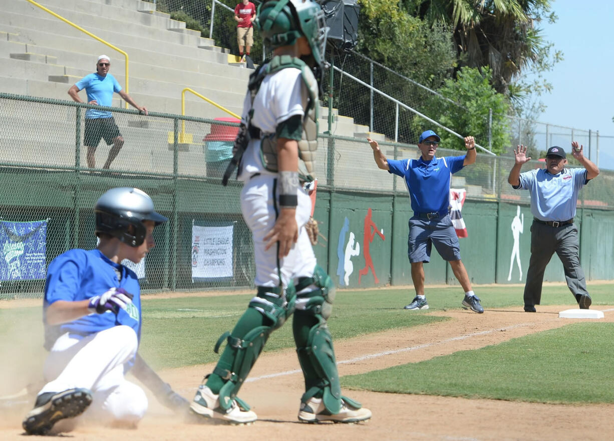 Cascade Little League third base coach Brendan McCarthy begins to celebrate the game tying run, scored by Mason Hill (left), as third base umpire George Rodriguez calls Hill out after McCarthy was called for aiding the runner ending the game. A coach is not allowed to touch a player while the ball is still in play. Cascade lost to Idaho 8-7 on Friday, August 14, 2015 ending their season at the Little League Northwest Regionals in San Bernardino, Calif.