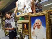 Carlos Limongi takes a shirt from a display of Pope Francis-related items at the gift shop within the Basilica of the National Shrine of the Immaculate Conception in Washington, D.C.