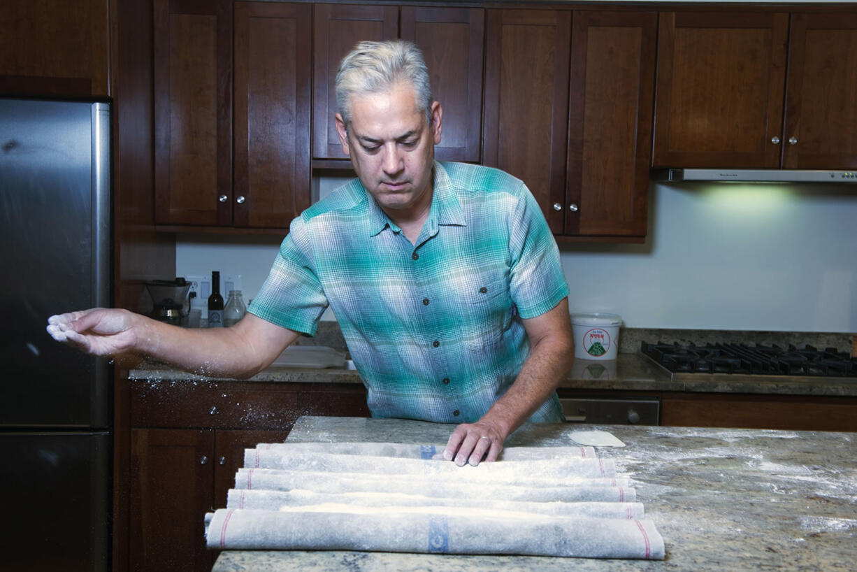 Samuel Fromartz dusts shaped baguette dough with flour in his kitchen; Fromartz is a journalist who covers, among other things, organic foods and the environment.