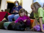 Sydney Pearce, 5, center, pets Holbrook, a 14-month-old black Lab who is a guide dog in training.