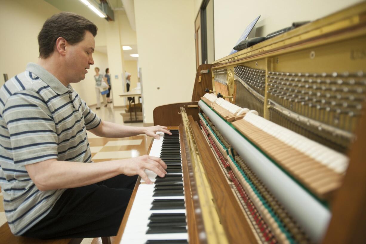 Piano tuner Sam Stahl tests a Kawai piano that was donated to the new Hough Early Learning Center. The School of Piano Technology for the Blind has launched a program connecting used-piano donors with appropriate placements.