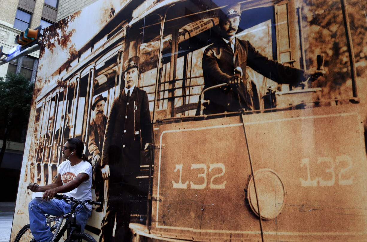 A man sitting on his bike is dwarfed by a mural on Sept.