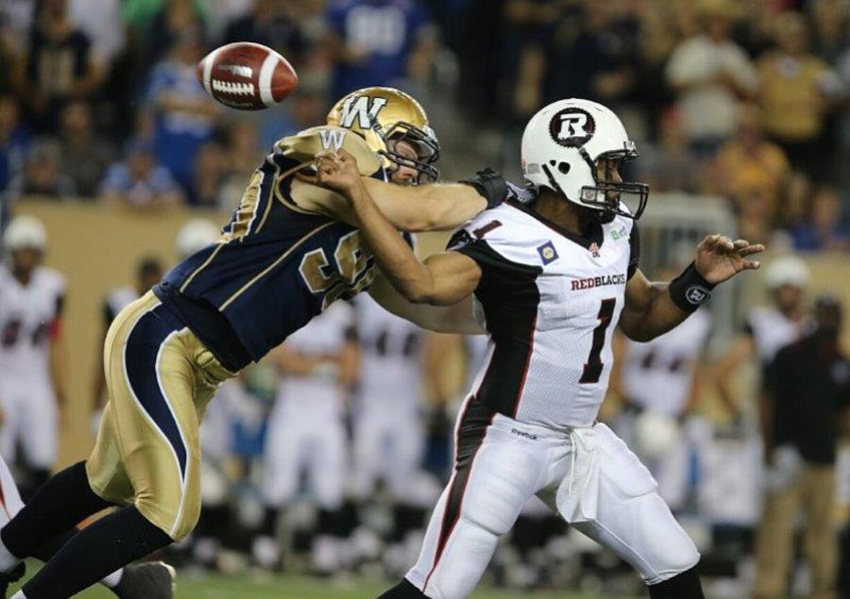 Winnipeg defensive end Greg Peach, left, forces a fumble in a Canadian Football League game against the Ottawa Redblacks.