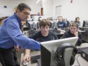 Frederick Tillman, computer teacher at Amboy Middle School, left, helps sixth-grader Ely Earl, center, in an Hour of Code puzzle.