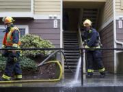 Firefighters Kevin Stromberg, left, and Joe Spatz spray down the sidewalk in front of an apartment building that caught on fire Wednesday in east Vancouver.