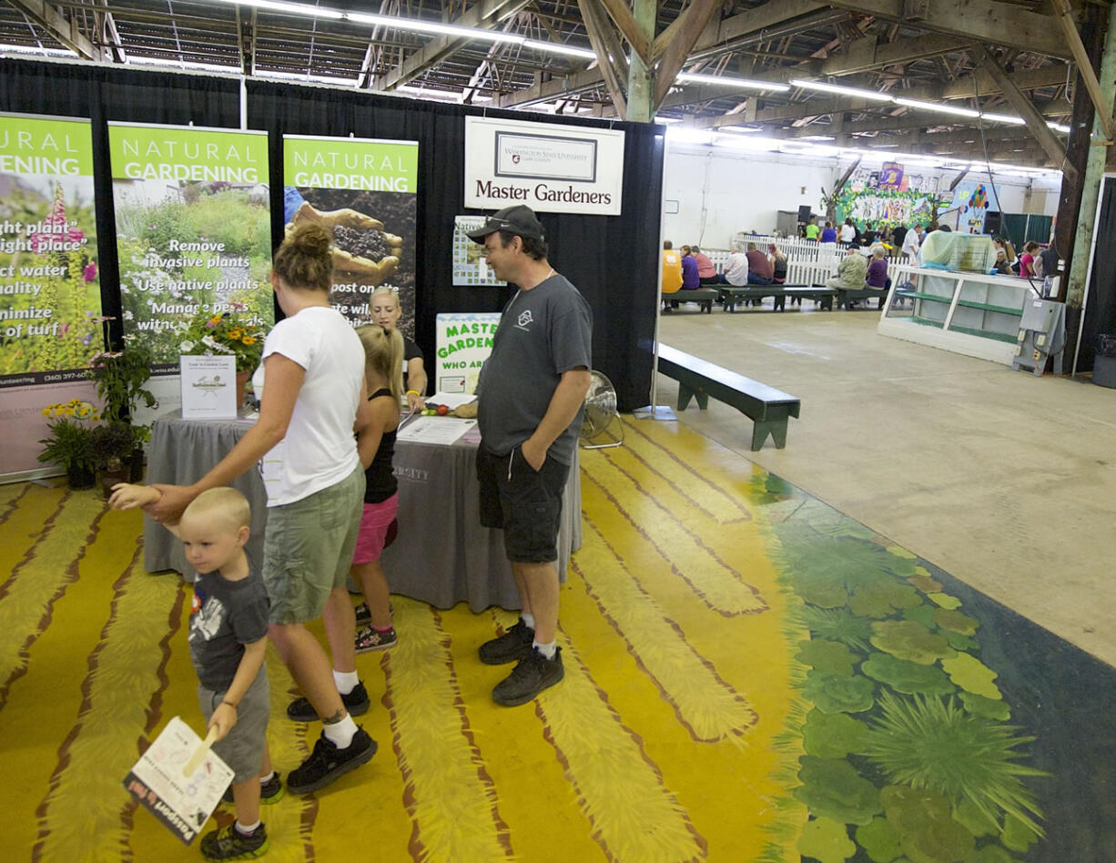 Don Philpott, center, visits the WSU Master Gardener booth at the Clark County Fair with his ex-wife Earlene Thurman and their grandchildren Mathew, 3, and Madeline, 6, on Tuesday.