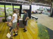 Don Philpott, center, visits the WSU Master Gardener booth at the Clark County Fair with his ex-wife Earlene Thurman and their grandchildren Mathew, 3, and Madeline, 6, on Tuesday.