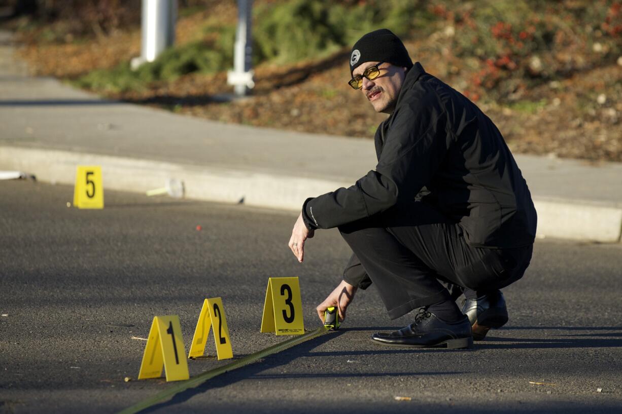 Vancouver police detective Lawrence Zapata investigates shell casings near the intersection of 33rd Street and St.