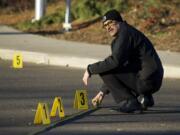 Vancouver police detective Lawrence Zapata investigates shell casings near the intersection of 33rd Street and St.