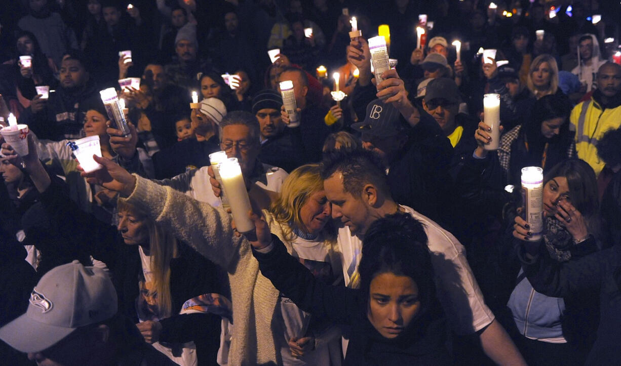 Kevin Boyer, right of center, is consoled by his mother, Cathy Boyer, at a candlelight vigil for his 7-year-old daughter, Cadence, who was struck by a car while trick-or-treating along Northeast 112th Avenue in east Vancouver and later died from her injuries.