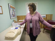 Clark County Public Health educator Sandi Kendrick looks down at a dummy used to demonstrate how to administer lifesaving measures given to clients in rescue kits, at the Harm Reduction Center.