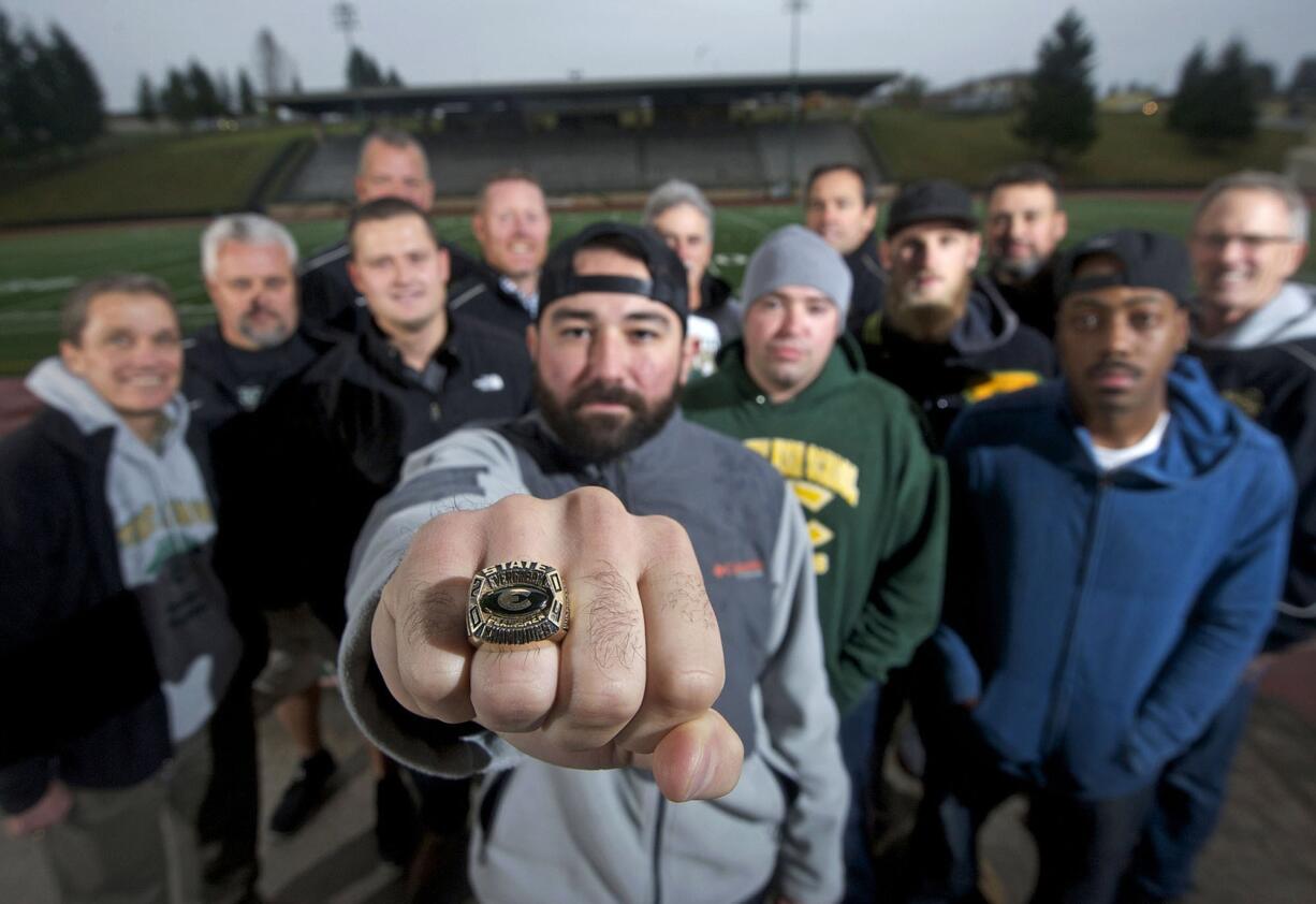 Nick Fleck, quarterback of the Evergreen High School football team in 2004, holds out his state championship ring with other members of the team and coaching staff.