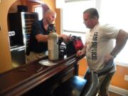 Brian Ackley of CSB Distributing, left, and owner Scott Flury of Latte Da Coffeehouse and Wine Bar get ready to install new beer taps in the back room at Latte Da.