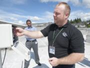 Facilities technician Adam Norman tests the pollen counting machine on the roof of The Vancouver Clinic Salmon Creek office as Dr. Raj Srinivasan looks on. Norman collects samples from the roof three days a week.