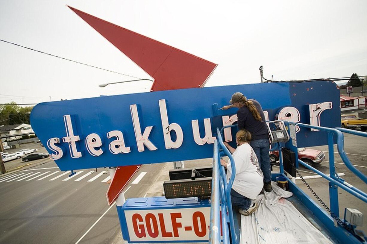 Ken Makowski, right, and Jackie Trengove from Pro-Cleaning and Maintenance Services paint the Steakburger restaurant sign on Northeast Highway 99 in Hazel Dell.