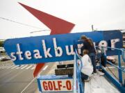 Ken Makowski, right, and Jackie Trengove from Pro-Cleaning and Maintenance Services paint the Steakburger restaurant sign on Northeast Highway 99 in Hazel Dell.