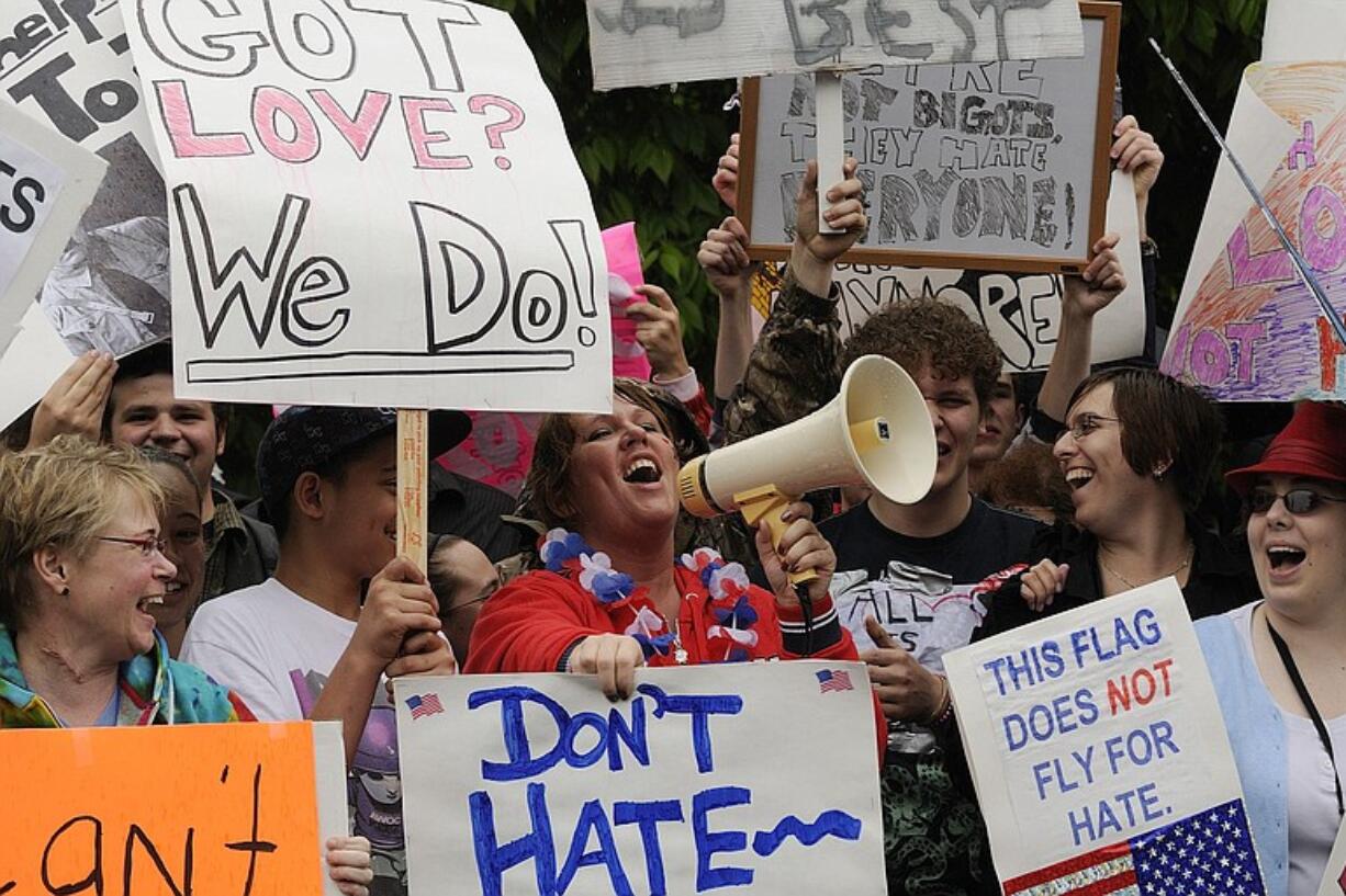 Kimberly Frost, center, uses a bullhorn to sing songs against a small number of Westboro Baptist Church members who picketed outside Heritage High School Tuesday.