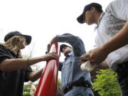 Sea Scouts, from left, Savannah Rova, 15, Taylor Torri, 17, and Ben Fillinger, 17, attach reflectors to new channel marker buoys.