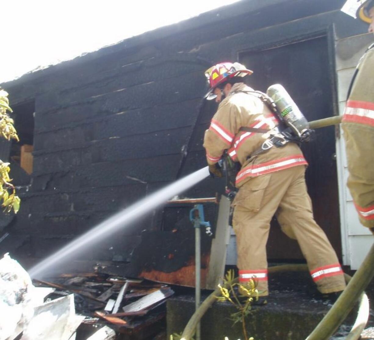 Firefighters douse a garage fire near the Walnut Grove area Tuesday, stopping flames from spreading to a nearby home and large trees.