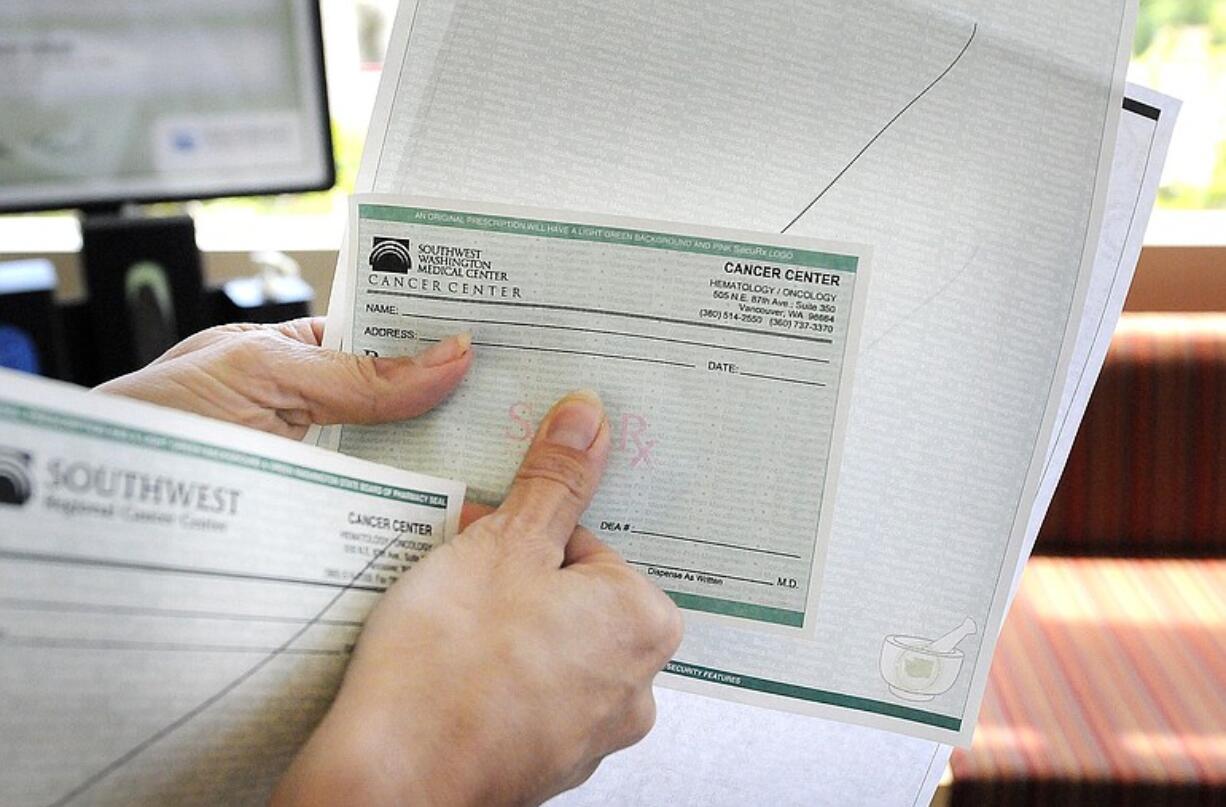 Becky Caswell shows the new state Board of Pharmacy seal on prescription pads Wednesday at the Southwest Washington Medical Center outpatient pharmacy. The ink changes colors when rubbed.