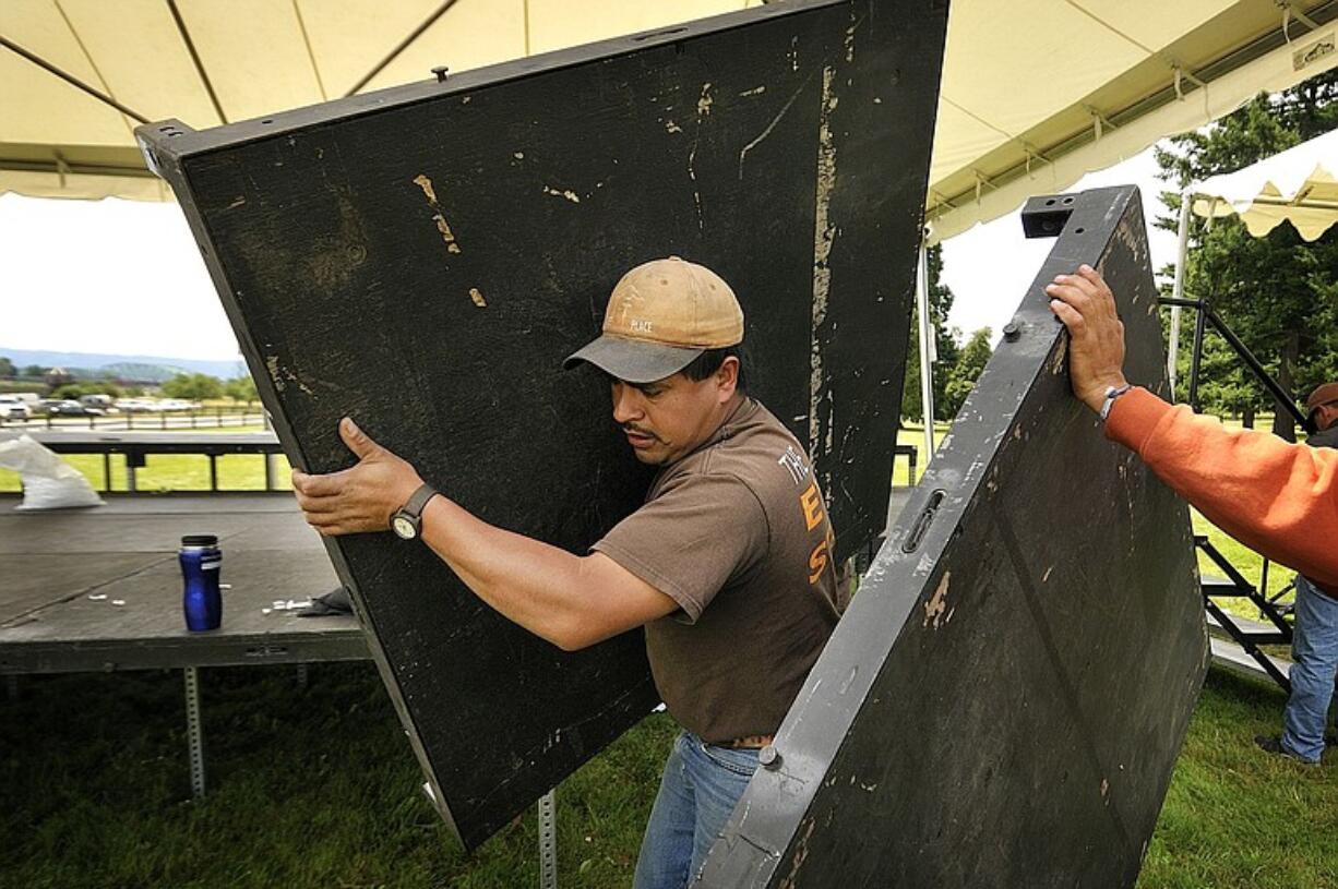 Mario Leon, a worker with The Party Place, helps take apart the main stage Monday at the Fort Vancouver National Historic Site, following Sunday's fireworks show.