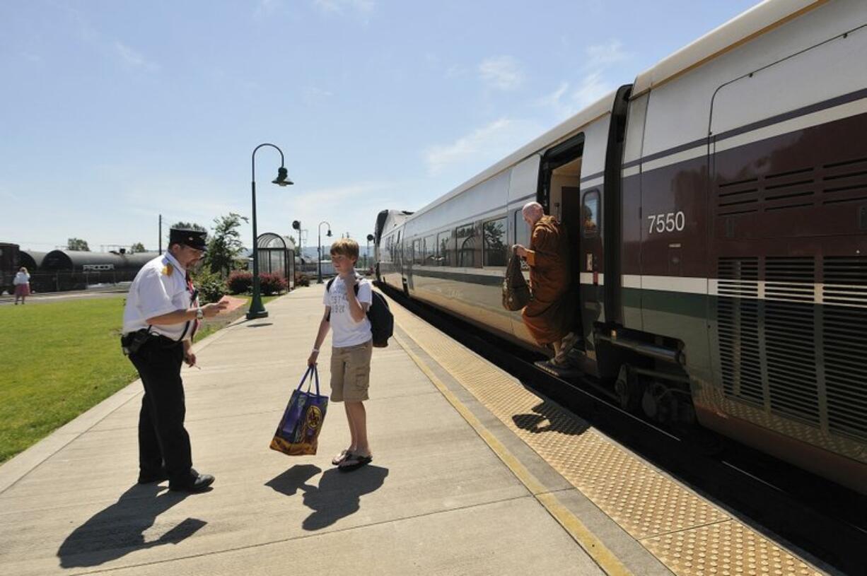 Passengers exit a southbound train at the Vancouver Amtrak station in Vancouver on Thursday. In the background on the left, rail tank cars at Albina Fuel hold heated liquid asphalt.