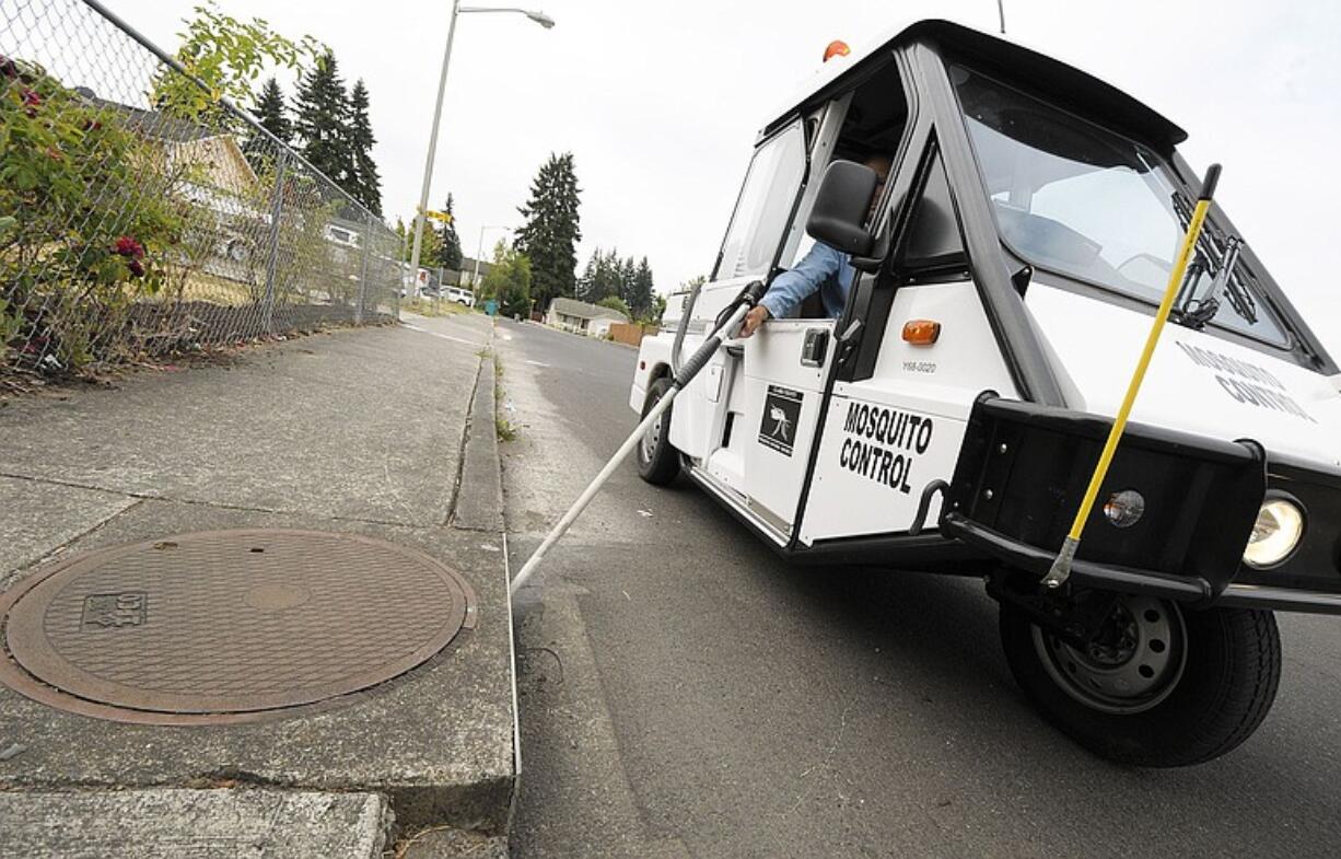 Clark County Mosquito Control District employee Kyle Kirby treats a storm drain near the intersection of Northeast 139th Avenue and 84th Street in Vancouver Wednesday.