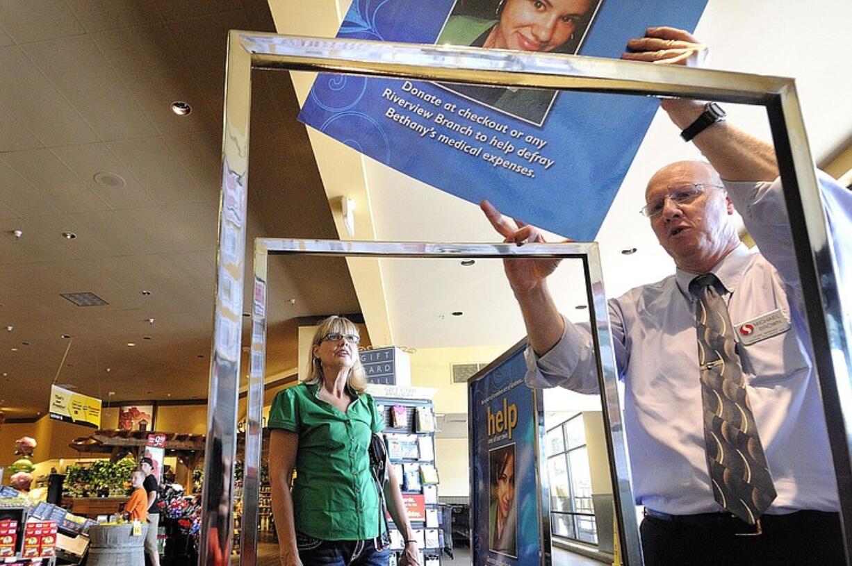 Michael Brown, right, a manager at the Safeway store in Washougal where Bethany Storro worked at the deli counter, places poster in display stands Friday as Nancy Neuwelt, Storro's mother, watches.