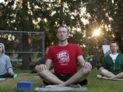 Zach Barnes meditates at the start of a yoga class taught by Emily Oliva in Arnada Park.