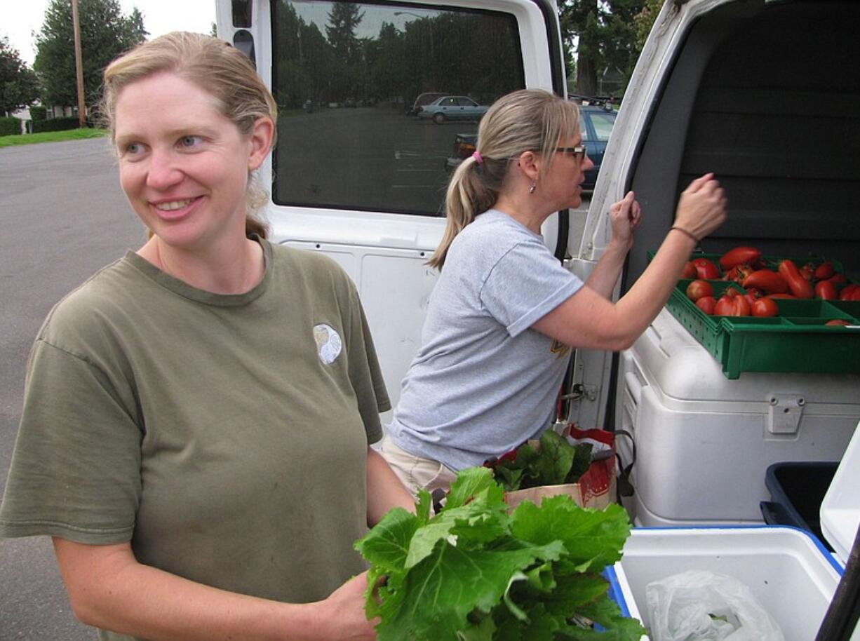 April Jones, an organic CSA farmer from Ridgefield, left, distributes fresh produce to Fruit Valley resident Michelle May.