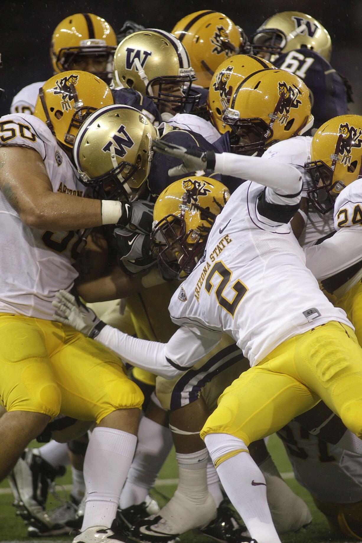 Washington's Chris Polk is brought down by Arizona State's Eddie Elder (2) and a host of teammates as he runs the ball in the first half Saturday.