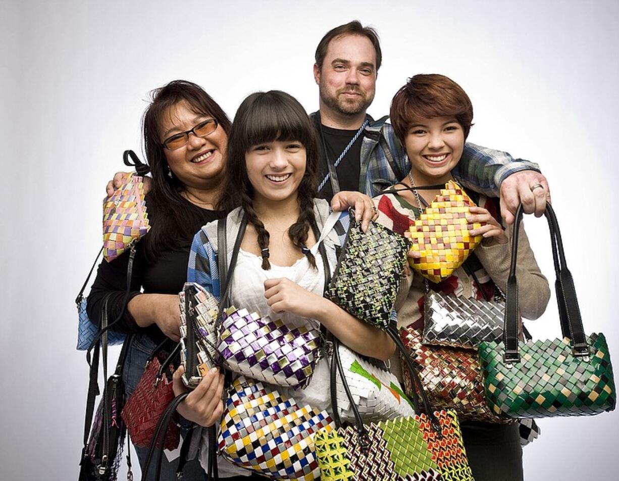 Stephanie and Matt Dukart with their kids, Briayne, 14, front left, and Kat, 16, show off handbags made from recycled material.